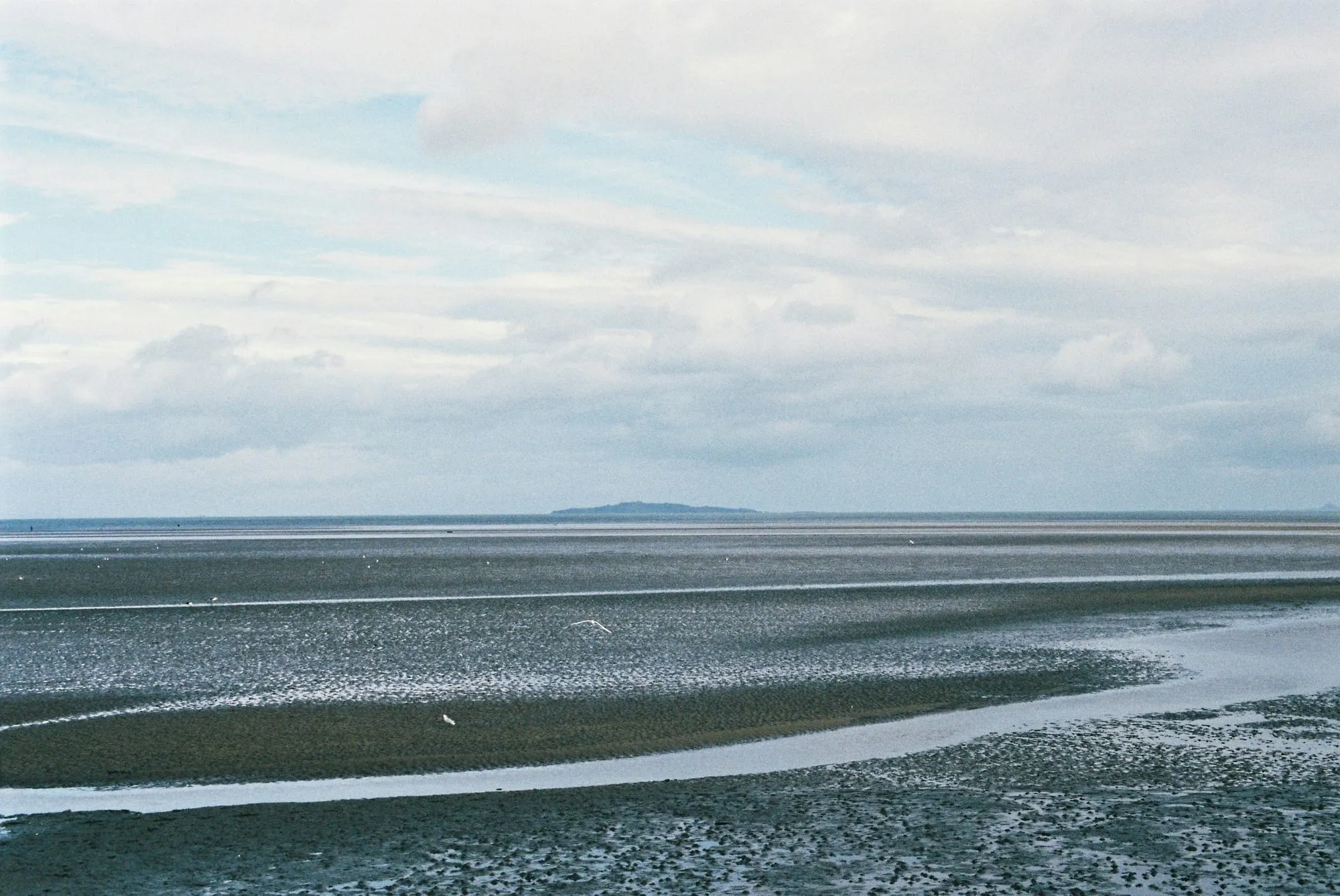 Ruhiges Meer und Watt unter weitem Wolkenhimmel